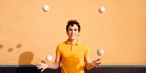 Agile man juggling balls near colorful wall
