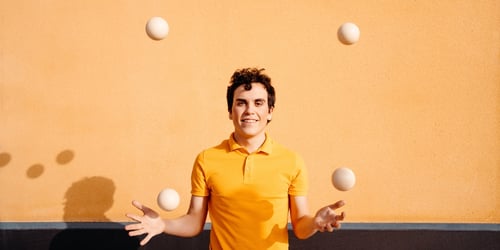 Agile man juggling balls near colorful wall, blogpost about building agile culture