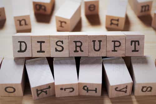 Small wooden cubes spelling the word 'Disrupt' talking about disruptive innovation vs. disruptive technology