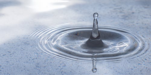 Abstract water drop in metal tray and splash on surface making circular waves