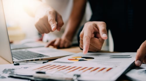  Person pointing at document on table analyzing business performance for blogpost on innovation vs. continuous improvement