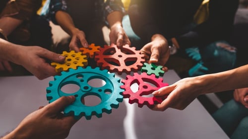People holding different color gears in their hands and holding them together. Blogpost about creativity myths. 