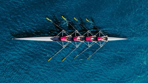 Rowing team on blue water.