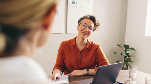 Happy person interviewing another person in an office. Blogpost about Human Resources in driving innovation forward.