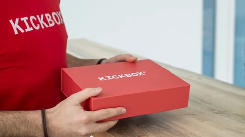 Person holding a red box with the word 'KICKBOX' on it. Blogpost about KICKBOX Intrapreneurship program.