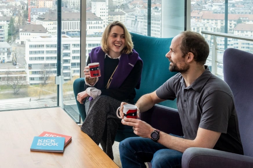 Two people having coffee and conversing in an office.