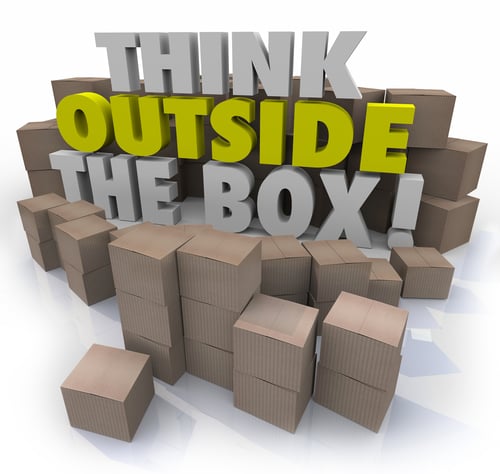 A stack of boxes with think outside the box written which is radical innovation